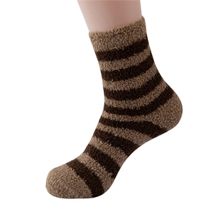 Close-up of men's brown striped coral fleece fluffy socks worn on foot with soft texture