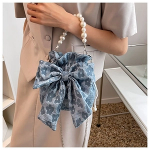 Blue jacquard bucket bag detail featuring large bow and white pearl top handle