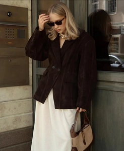 Détail d'une veste mi-longue en daim marron foncé avec boutonnage simple et texture mate