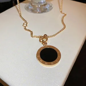 Gros plan du collier doré avec pendentif chiffres romains et détail de la lettre B