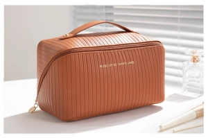 Detailed view of caramel vertical textured leather makeup bag with gold zipper and handle