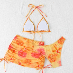 Detailed flat lay of three-piece hibiscus print bikini set with matching sarong skirt