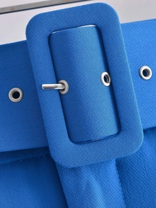 Detalle de pantalón azul de cintura alta con hebilla forrada de tela y ojales metálicos