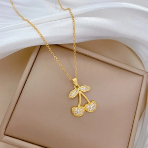 Elegant gold cherry pendant necklace with white crystals on silk fabric background