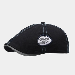 Detail of black cotton flat cap featuring contrasting blue stitching and a circular patch