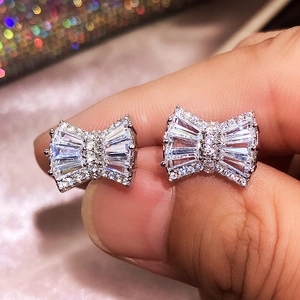 Macro shot of silver bow stud earrings with clear zircon stones and polished finish