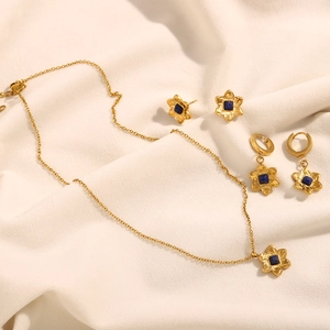 Detailed view of 18K gold plated flower necklace and earrings set with blue gemstones