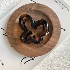 Close-up of a brown butterfly hair claw clip with tortoise shell texture on a wooden coaster