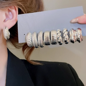 Macro detail of various silver textured C-shape hoop earrings and on-model display
