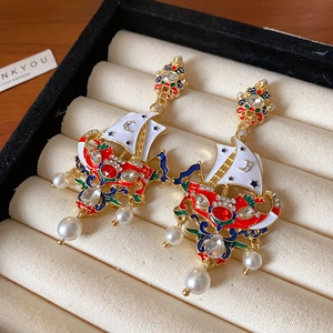 Detailed macro view of vintage gold sailing boat earrings with enamel and pearls