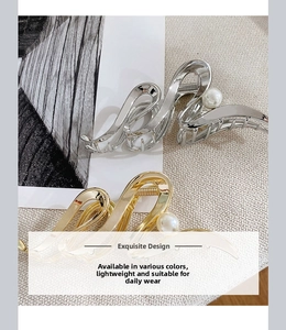 Detail of large metal hair claws in gold and silver finish with white pearl accents