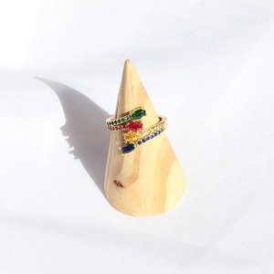 Detail of a vintage golden ring with four colorful oval gems on a wooden cone stand