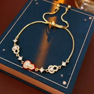 Macro shot of gold plated gourd bracelet with red heart ruyi charm and pearls