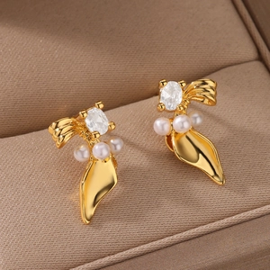 Detail of 18K gold heart earrings with zircon bow and white pearls on velvet display