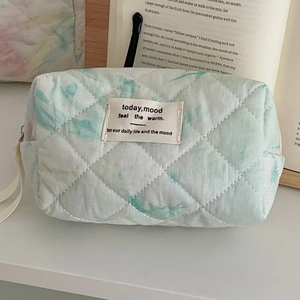 Close-up of quilted tie-dye cosmetic bag featuring blue-green patterns and zipper detail