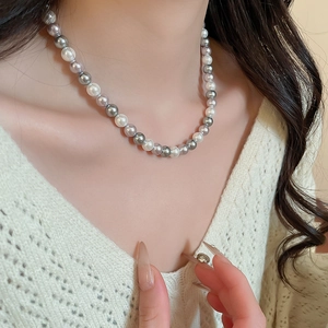 Close-up of French pearl necklace with white and grey beads worn on a neck