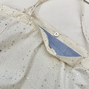Detail of canvas tote bag with silver star prints, metal magnetic closure and striped lining