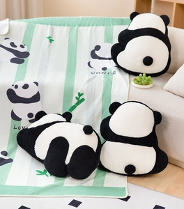 Detailansicht der Panda-Plüschkissen und der gestreiften Decke auf einem gemütlichen Sofa