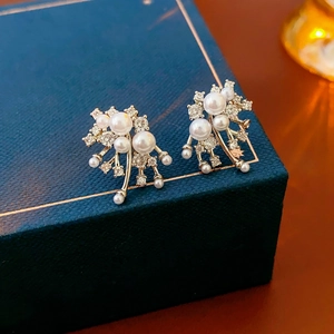 Macro shot of elegant fireworks pearl stud earrings with rhinestones on a jewelry box