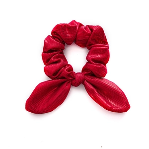 Red Christmas bow hair scrunchie made of metallic textured fabric on white background