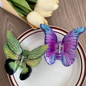 Close-up of butterfly hair claws with gradient patterns and realistic vein textures