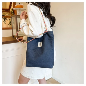 Détail du sac cabas en jean bleu avec bandoulière tissée et doublure rouge