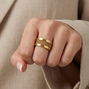 Detailed macro view of wide gold mesh woven ring with polished edges on hand