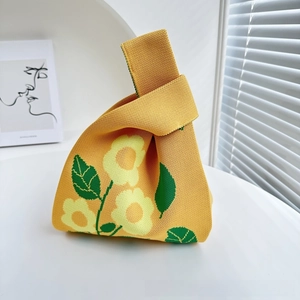 Detail of yellow knitted knot bag featuring delicate floral patterns and woven texture