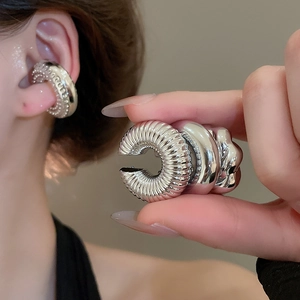 Vue macro d'un earcuff argenté poli avec un motif détaillé de vis en spirale torsadée