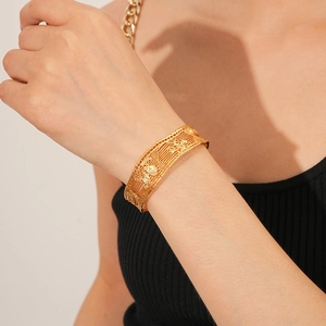 Close-up of 18k gold-plated cuff bracelet featuring intricate hollow grid patterns