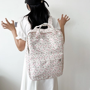 Back view of model wearing the floral canvas backpack in a minimalist white setting