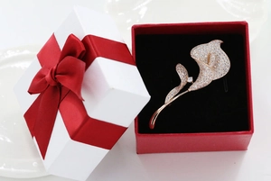 Detailed view of rose gold calla lily brooch with inlaid crystals in a gift box