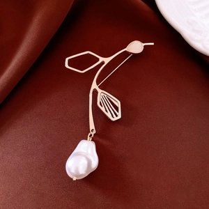 Macro detail of bird brooch with pink gemstone and baroque pearl on silk fabric