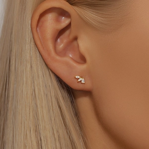 Close-up of model wearing gold stud earrings featuring a fan-shaped triple zircon design