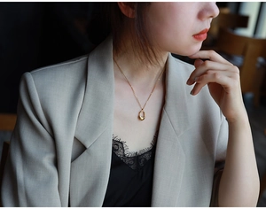Minimalist gold teardrop pendant necklace worn by female model in office style