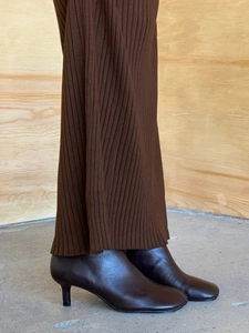 Detail view of dark brown leather stiletto boots paired with a brown knitted dress