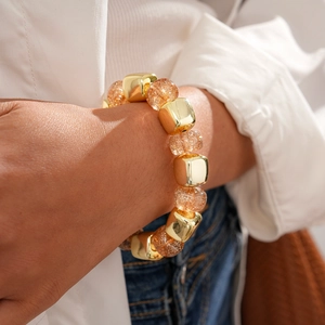 Detail of amber acrylic and gold beaded bracelet worn on wrist for a vintage look