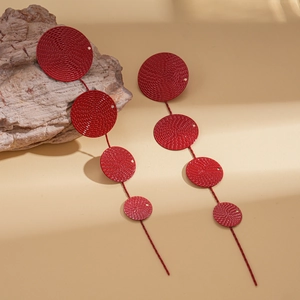 Deep red metallic textured circle drop earrings on a light stone and beige background