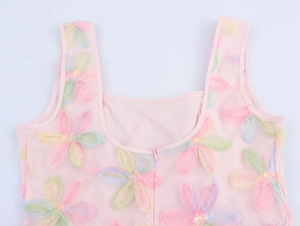 Detailed close-up of 3D colorful floral appliques and sequins on pink mesh fabric