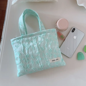Detail view of mint green jacquard tote bag featuring simple wish logo and soft texture