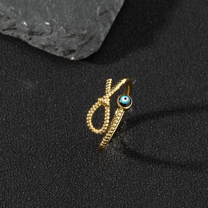 Macro shot of gold-toned evil eye ring featuring a braided rope texture and blue enamel inlay