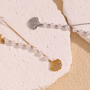 Detail of 18K gold and silver necklaces with shell pendants on textured stone