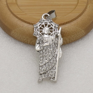 Gros plan d'un pendentif religieux en argent serti de cristaux sur support en bois