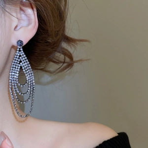 Detail of long multi-layered tassel earrings with silver rhinestones on black metal base