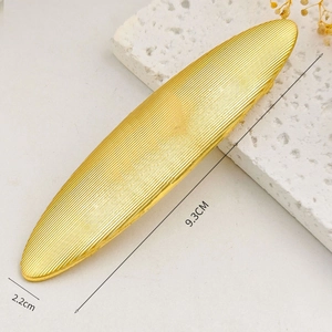 Macro detail of a 9.3cm gold alloy hair clip with texture on white stone background