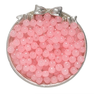 Detailed top view of pink glass apple beads in a decorative silver container for DIY
