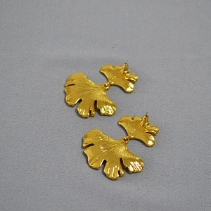 Exaggerated vintage brass gold plated ginkgo leaf earrings on textured grey background