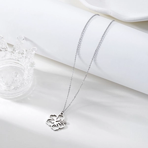 Detailed view of silver stainless steel necklace with hollow flower pendant on white stand