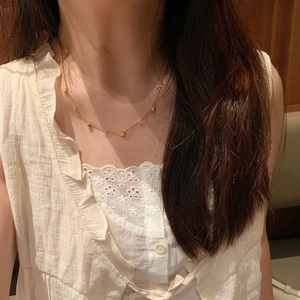 Dettaglio di collana dorata minimalista con perle tonde e pietre su collo femminile