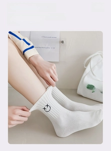 Nahaufnahme weißer Baumwollsocken mit hoher Elastizität und kleiner Smile-Stickerei am Saum